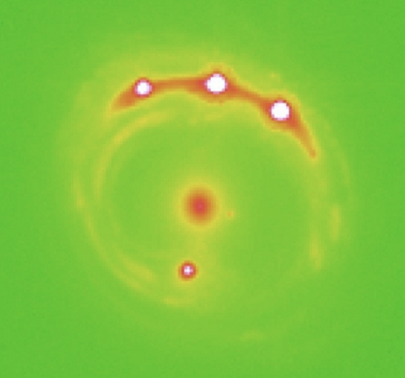 El cuásar RXJ 1131−1231 distorisonado por efecto de lente gravitatoria de una galaxia más cercana (University of Oklahoma).